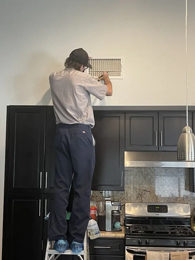 Technician inspecting an air vent during HVAC service in Fort Dodge